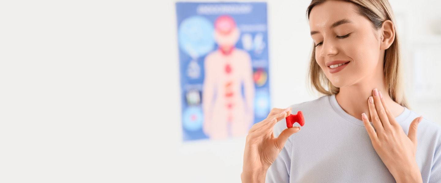 Жінка тримає модель щитоподібної залози — здоров’я ендокринної системи та гормональний баланс