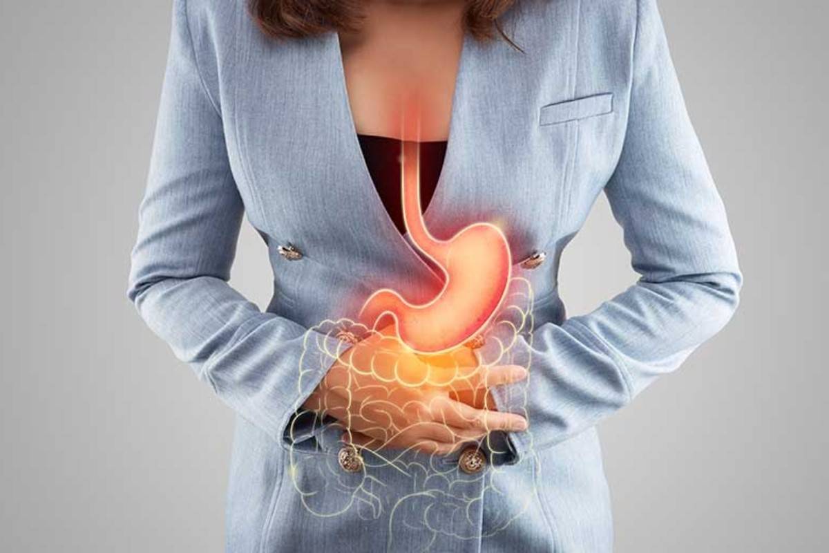 Жінка тримається за живіт, ілюстрація шлунка та травної системи при болю в шлунку.
