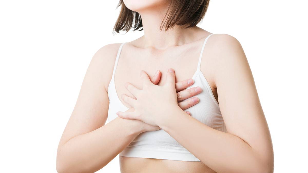 Жінка притискає руки до грудей, самостійна перевірка грудей.